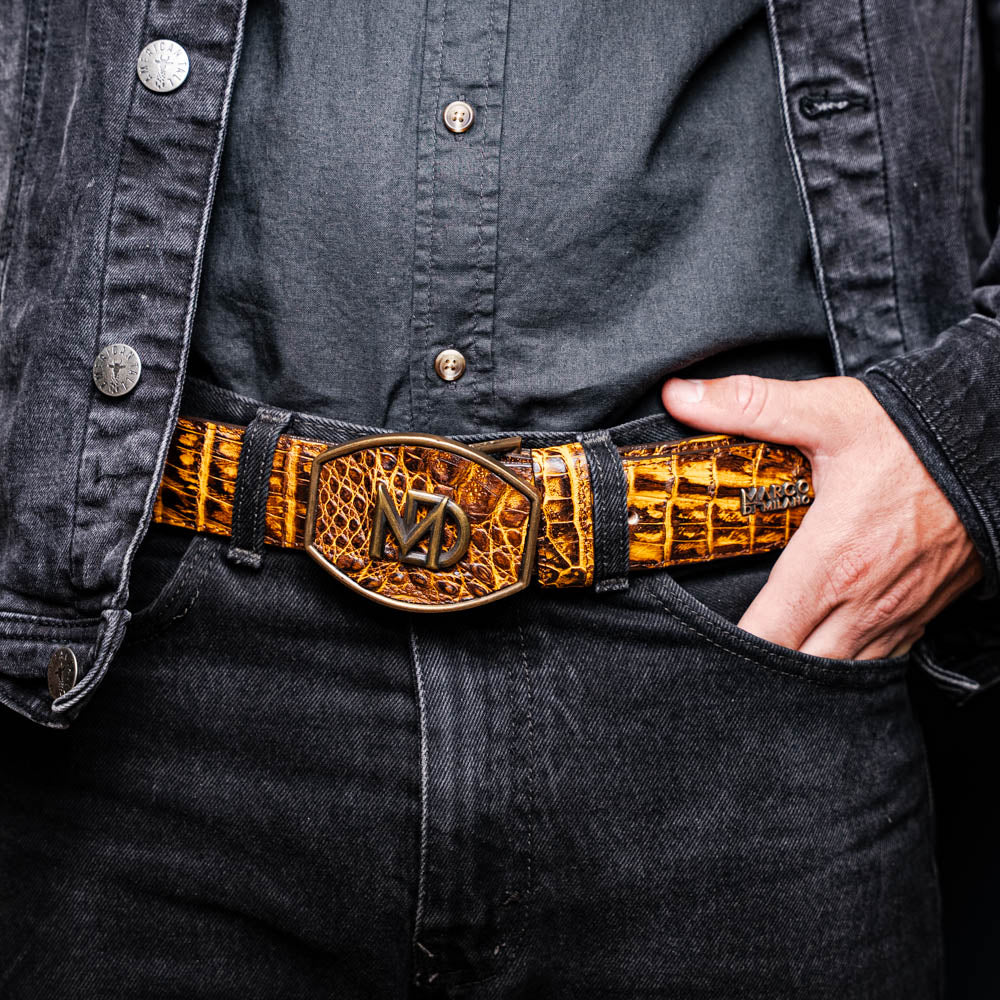 Man wearing Iowa Belt Mustard Brown made of genuine caiman skin with antique brass buckle, showcasing bold Western craftsmanship.