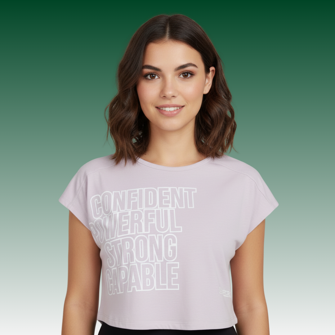 Woman wearing LA Gear Women’s Cropped Logo Tee | Lavender-Pink with motivational text on green gradient background.