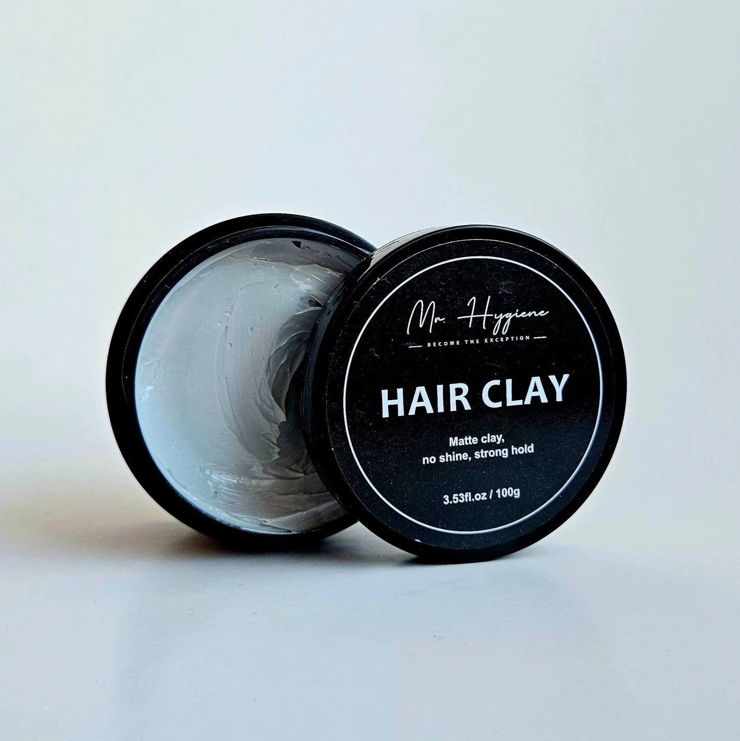 Matte Finish Hair Clay - Strong Hold. Zero Shine. All-Day Control. 100g container with open lid displaying clay texture