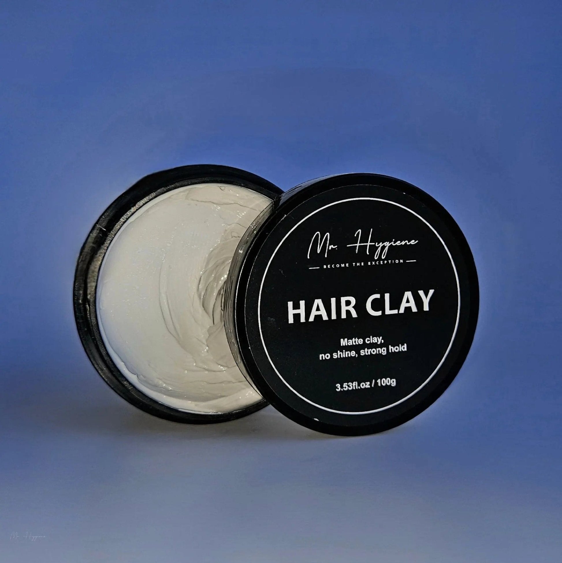 Matte Finish Hair Clay - Strong Hold. Zero Shine. All-Day Control. in 100g open container against blue background.