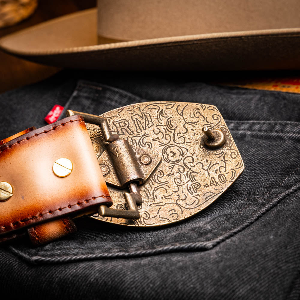 Montana Belt Stone Brown, hand-stitched caiman and calfskin Western belt with engraved buckle, displayed with a cowboy hat.