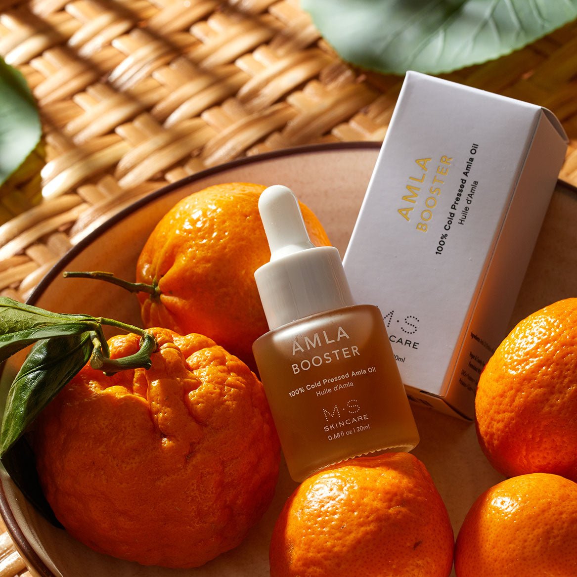 AMLA OIL bottle surrounded by fresh oranges, showcasing the antioxidant-rich skincare product with vitamin C benefits.