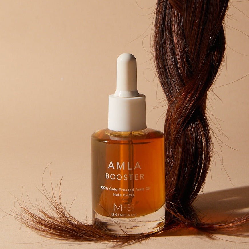 AMLA OIL booster next to healthy hair showcasing benefits for skin and hair health