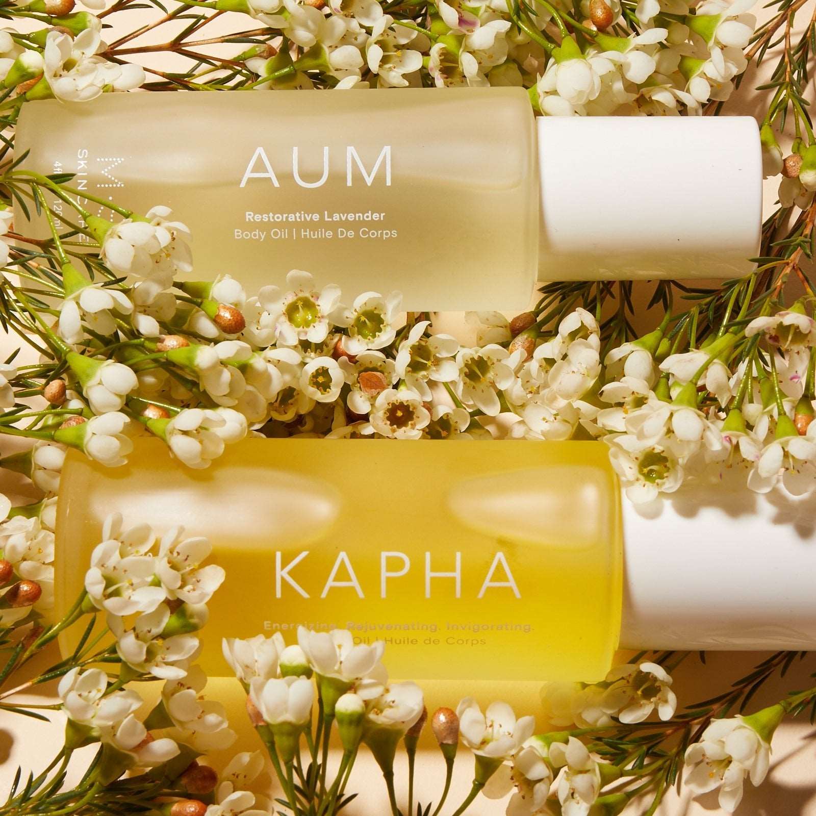AUM Ayurvedic Lavender body oil with coconut oil, gotu kola, and kakadu plum benefits, surrounded by flowers.