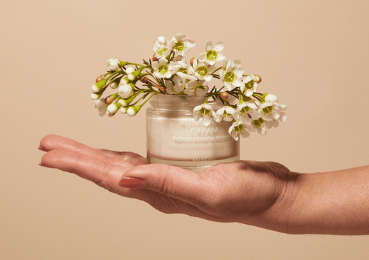ROSEWATER CREAM jar held in hand with white flowers, featuring Ayurvedic oils and organic extracts for radiant skin