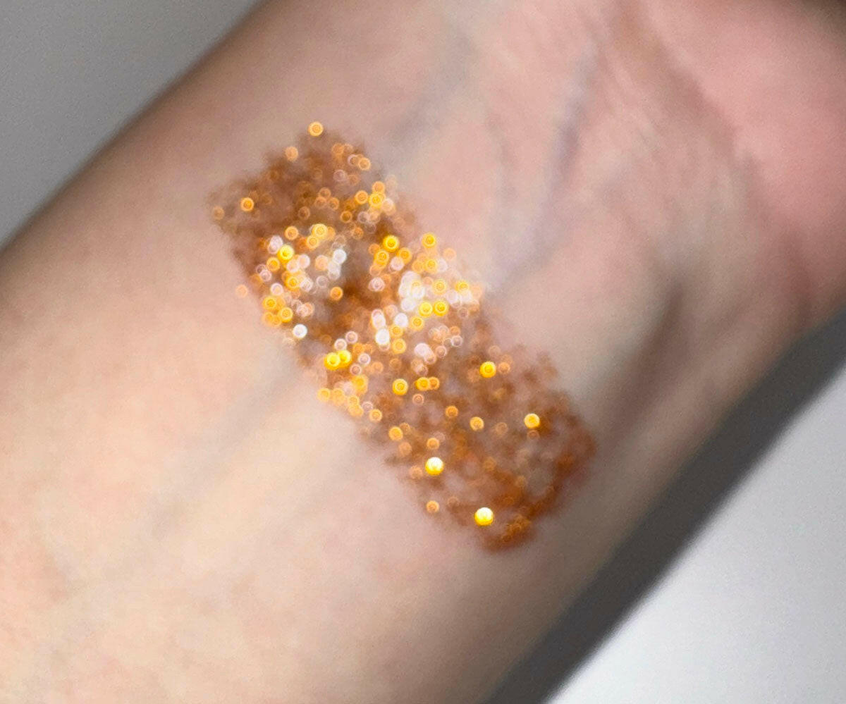 Swatch of Mystic - Flicker Glitter Eyeliner in copper glitter shade on skin.