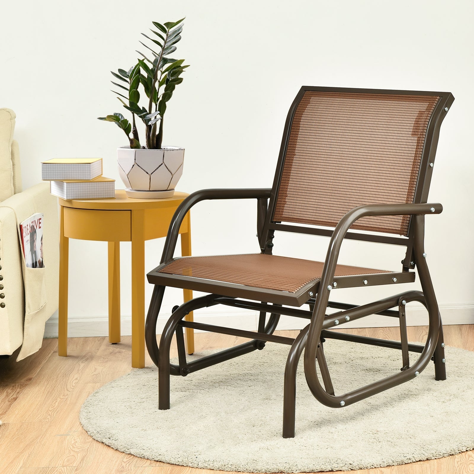 Outdoor Single Swing Glider Rocking Chair with Armrest-Brown in a living room setting with a side table and plant
