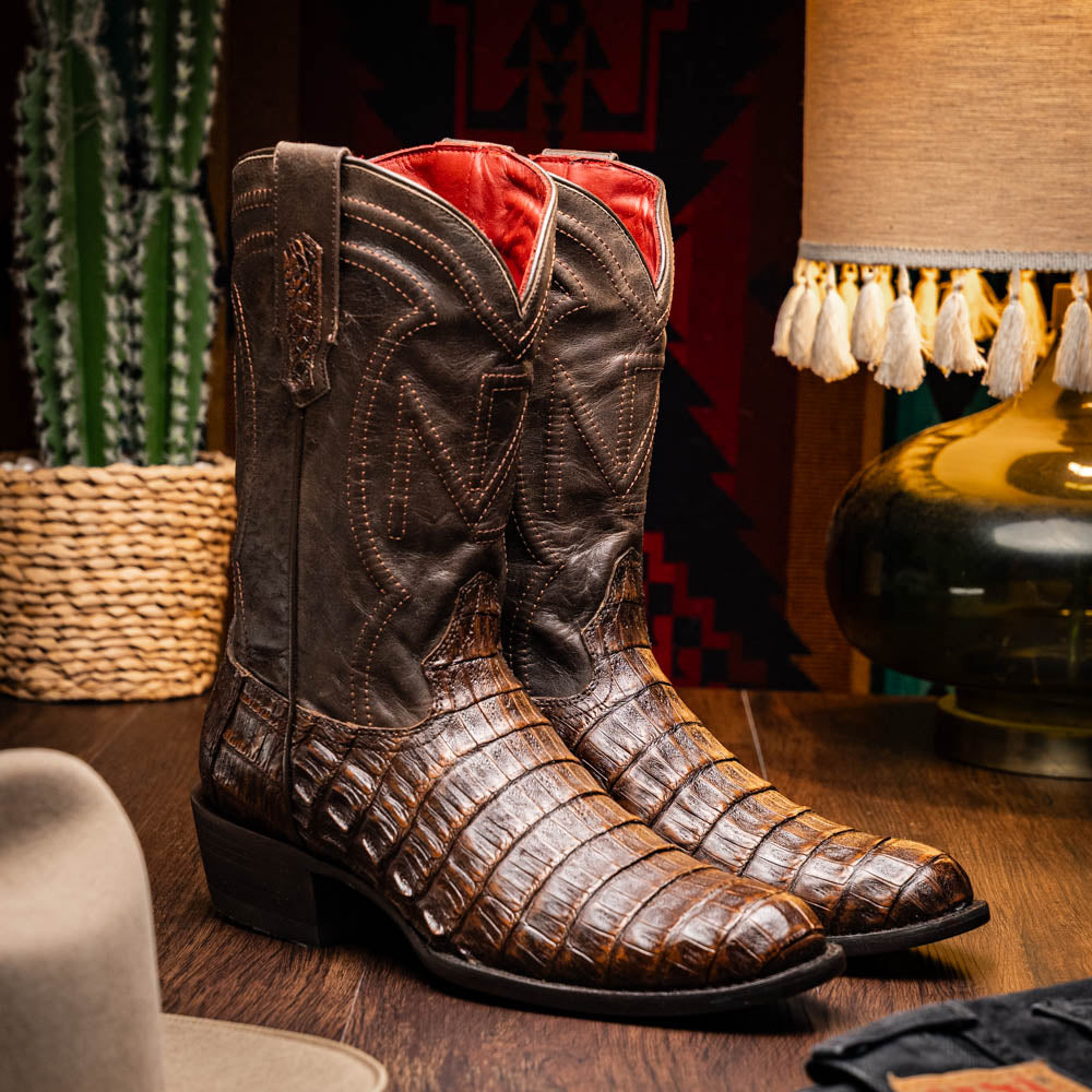Phoenix Aged Brown cowboy boots with caiman belly skin and leather shaft in a rustic setting