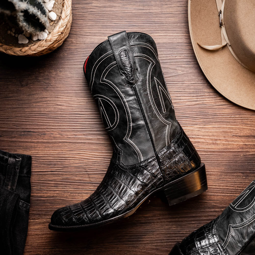 Phoenix Black cowboy boot with genuine caiman belly skin and full-grain leather, showcasing Western style on wooden floor.