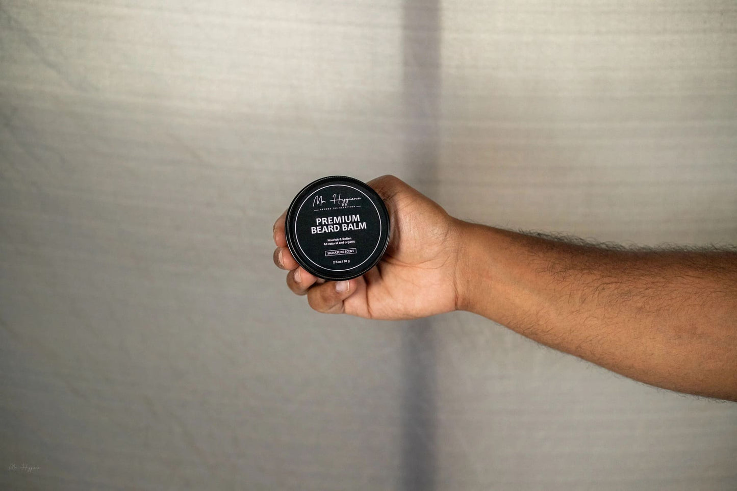Hand holding Mr. Hygiene's Premium Beard Oil and Balm Set for ultimate beard care