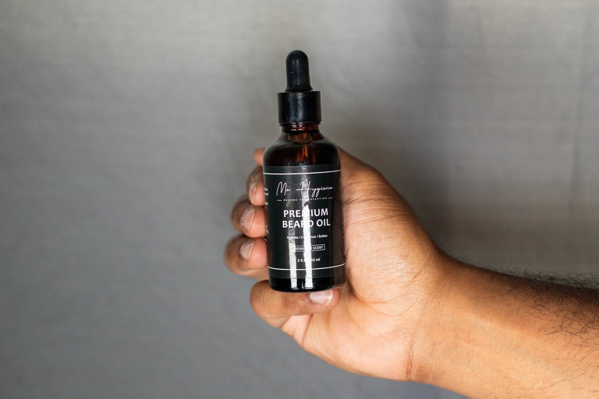 Hand holding a bottle of Premium Beard Oil for men's grooming and beard nourishment.