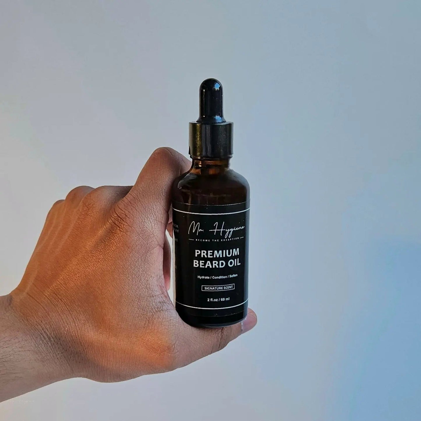 Hand holding a bottle of Premium Beard Oil with nourishing and hydrating properties for men.