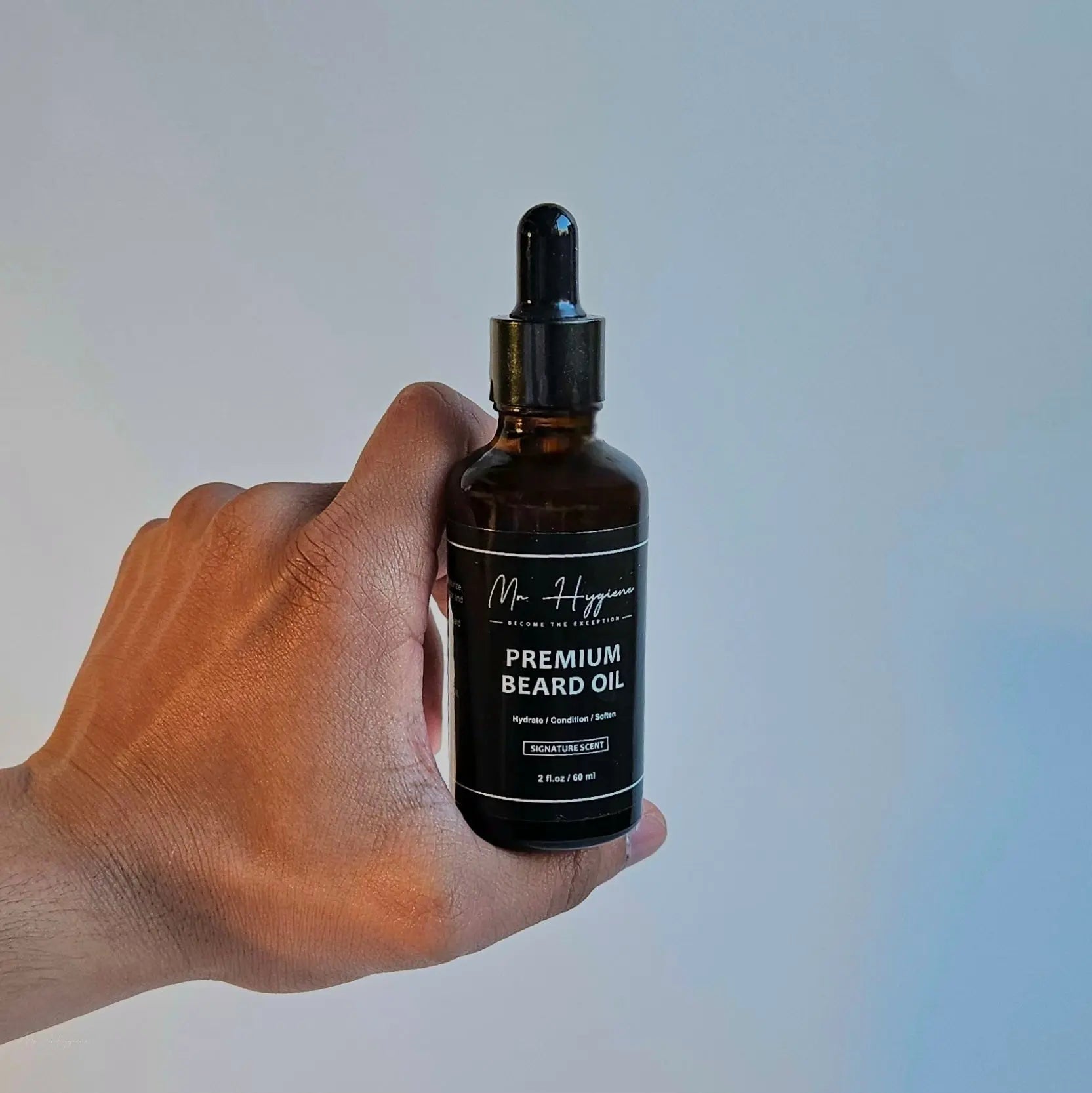 Hand holding a bottle of Premium Beard Oil with nourishing and hydrating properties for men.