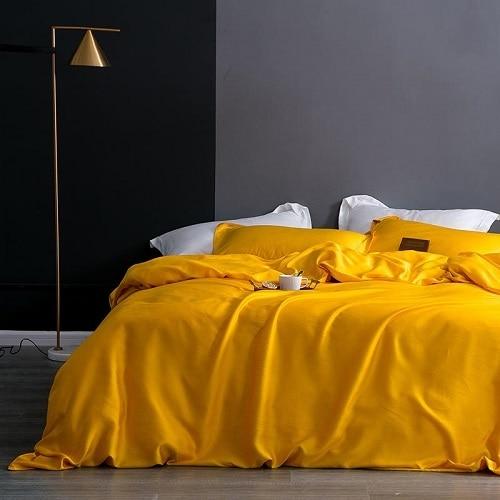 Karen Solid Color Lyocell Duvet Cover Set in bright yellow on a modern bed with a black and gray background.