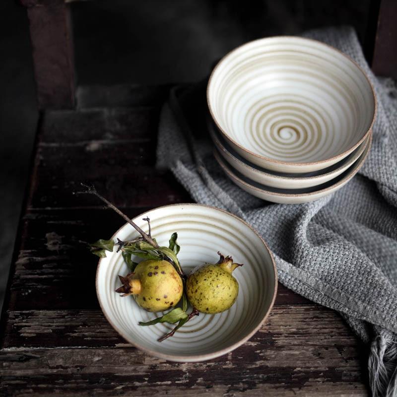 Hand-made Japanese Style Plates And Bowls stacked with fruit on a rustic table, showcasing ceramic craftsmanship and artistic design.