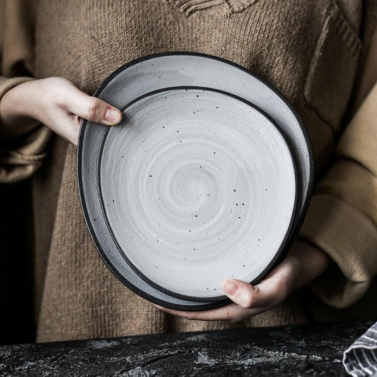 Person holding Lena Nordic Style Steak Plate And Coffee Set, handmade round ceramic plates with solid pattern, Nordic design