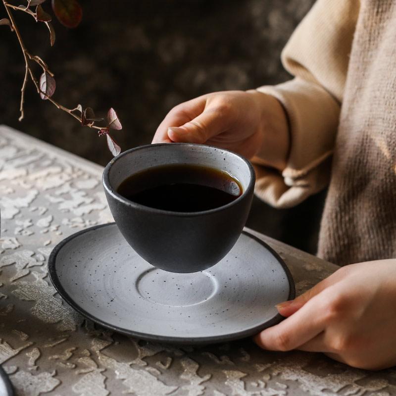 Person holding a ceramic coffee cup from the Lena Nordic Style Steak Plate And Coffee Set on a textured table.