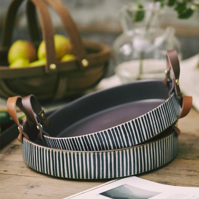 Exclusive Striped Ceramic Plate with Leather Handle, hand-painted porcelain, displayed on a rustic wooden table for home decor.