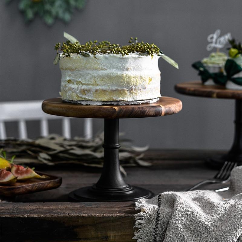 Tall European Wooden Cake Tray displaying a round, solid-patterned cake on a rustic dining table.