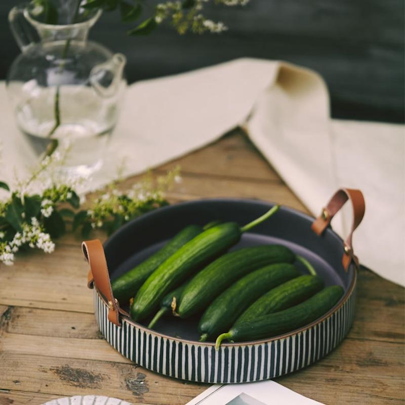 Exclusive Striped Ceramic Plate with Leather Handle displaying fresh cucumbers on a wooden table, eco-friendly and hand-painted.