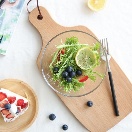 Fresh salad in French Letter Glass Bowl on wooden board beside strawberry cake, highlighting the bowl's elegant solid glass design.