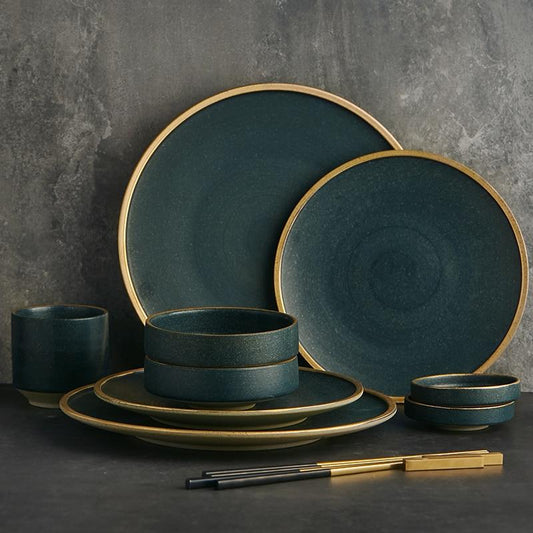 Galileo Tableware set with minimalist design, handcrafted porcelain plates in matte green with golden ring, displayed elegantly.