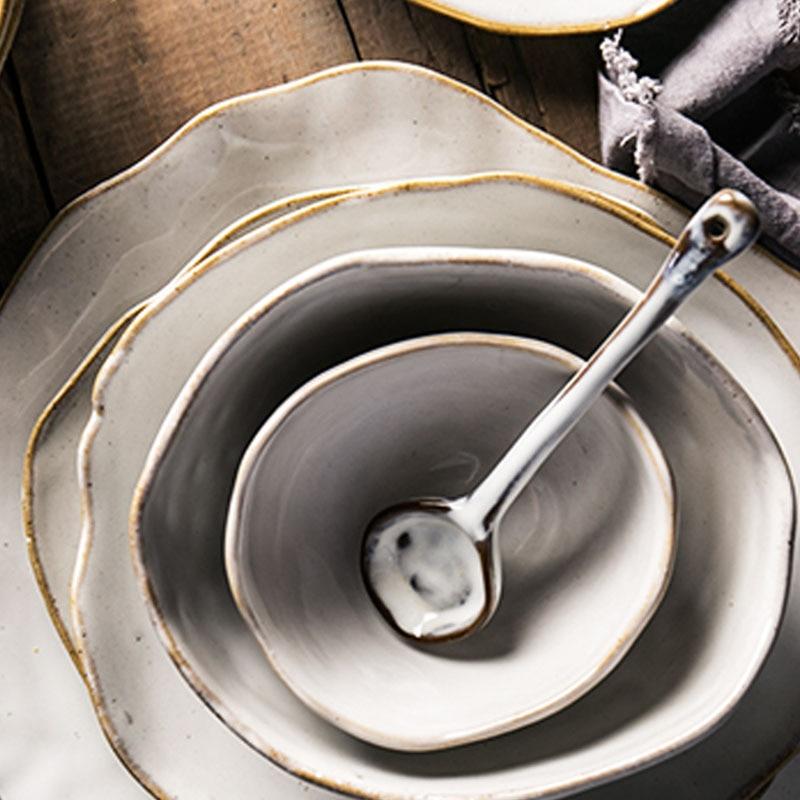 Nanna Bowls And Dishes from Thetis Tableware Set, showcasing elegant design with layered plates and a spoon on rustic wood