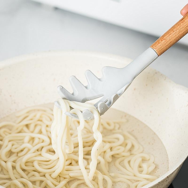 Premium Silicone Cooking Set Tools with wooden handle lifting noodles from a pot, ideal for microwave, oven, toaster, and steamer use.