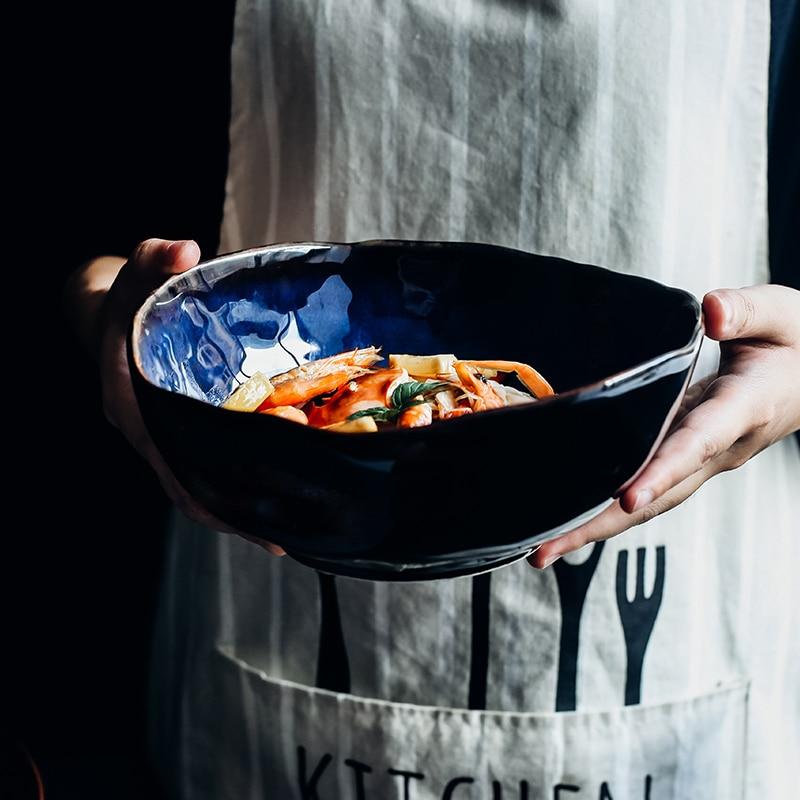 Hand holding a Blue European Porcelain Deep Bowl with food, showcasing dark blue glaze and eco-friendly design. Imported artisan quality.
