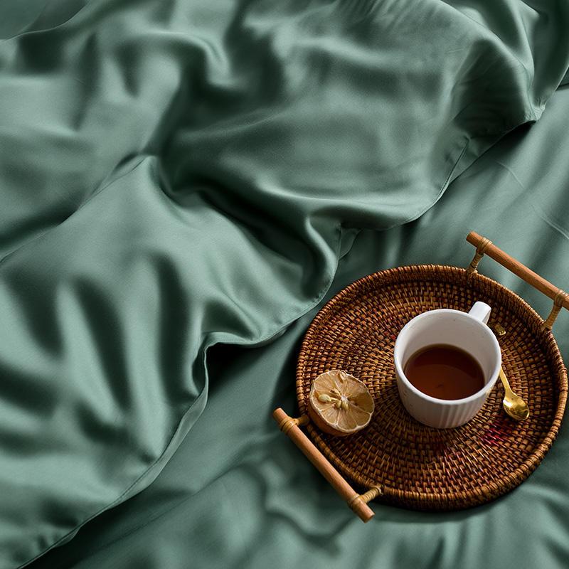 Karen Solid Color Lyocell Duvet Cover Set in green featuring a cup of tea on a wicker tray, showcasing modern and boho style.