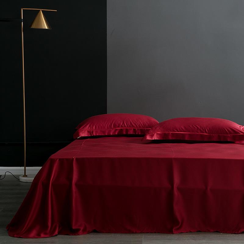Karen Solid Color Lyocell Duvet Cover Set in red on a bed, showcasing modern boho style and luxurious fabric, against a dark wall.