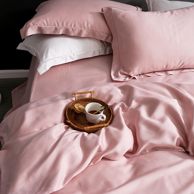 Karen Solid Color Lyocell Duvet Cover Set in pink displayed on a bed with matching pillows and a tray with cup and saucer.