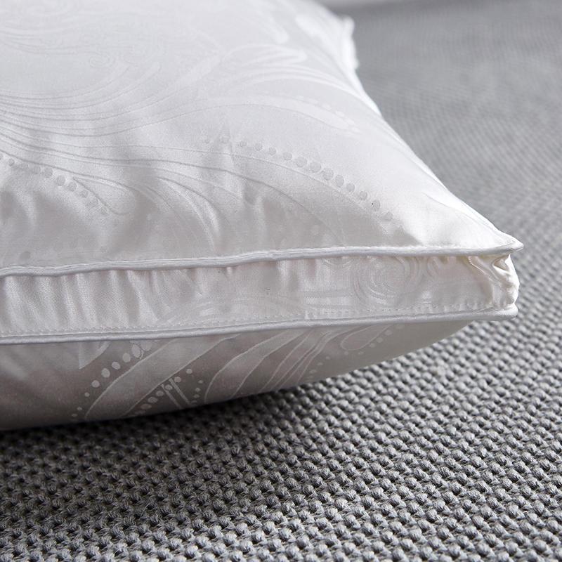 Close-up of Vincenzo Pillows Set of 2 Goose Down showing white fabric with subtle texture and stitching detail on a textured grey surface.