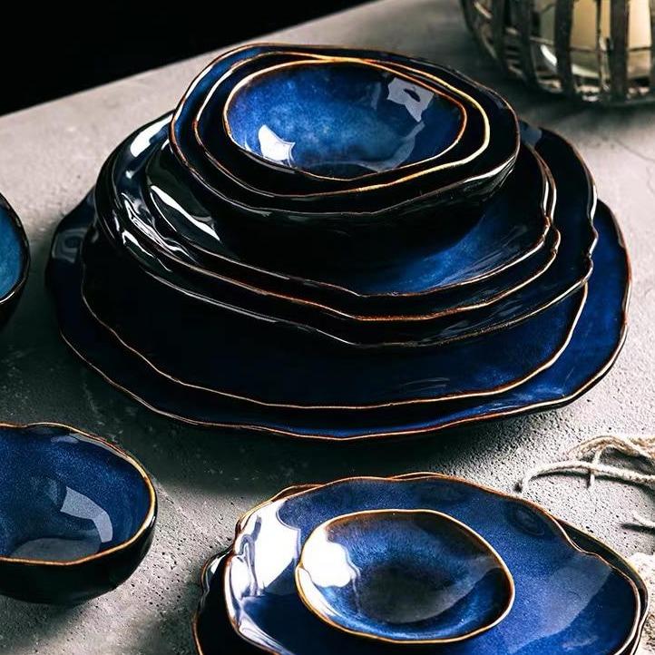 Blue European Porcelain Dinnerware Set (Plates and Bowls) from Amelia Collection with hand-painted dark blue hues on a table.