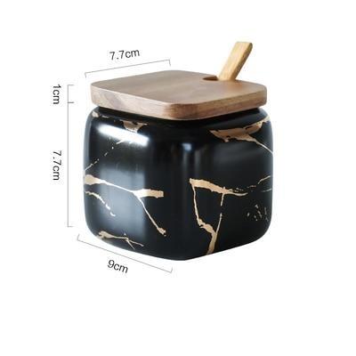 Maci 8-Piece Spice Ceramic Jar With Wooden Lid featuring a sleek black design with a gold marbled pattern and wooden spoon.