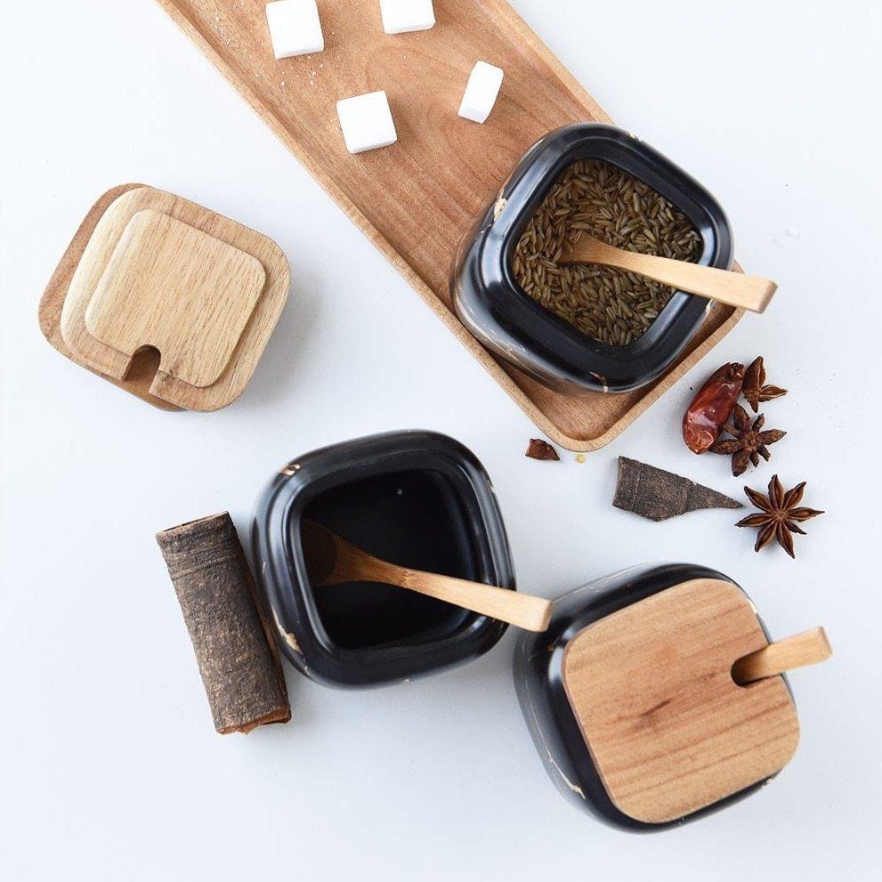 Maci 8-Piece Spice Ceramic Jar With Wooden Lid, featuring ceramic jars with wooden lids filled with herbs and spices.