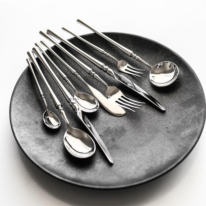 Zina Flatware Set 24-Piece (Polished) displayed on a black plate showcasing modern design and gleaming stainless steel utensils.