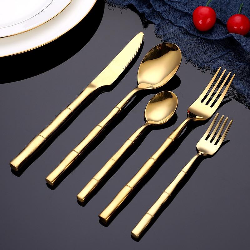 Lotus Flatware 24-Piece Set featuring gold bamboo style handles on black background with cherry accents.