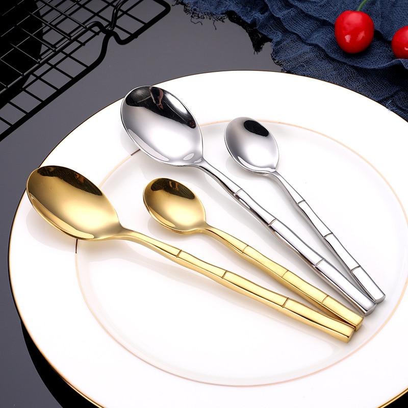 Lotus Flatware 24-Piece Set showing shiny bamboo-style handle spoons in gold and silver on a plate.