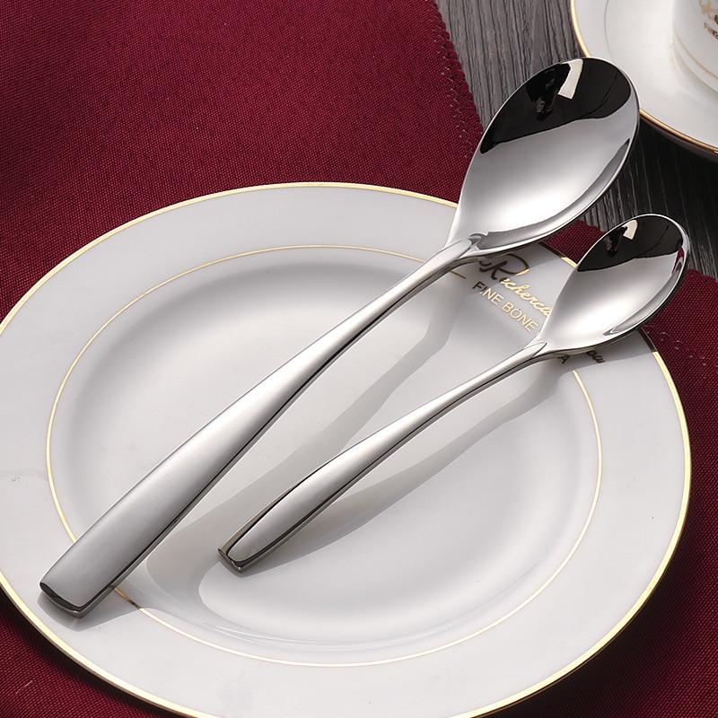Talia Shiny Silver Flatware 24-Piece Set with elegant polished spoons on a china plate, ideal for formal and everyday dining.