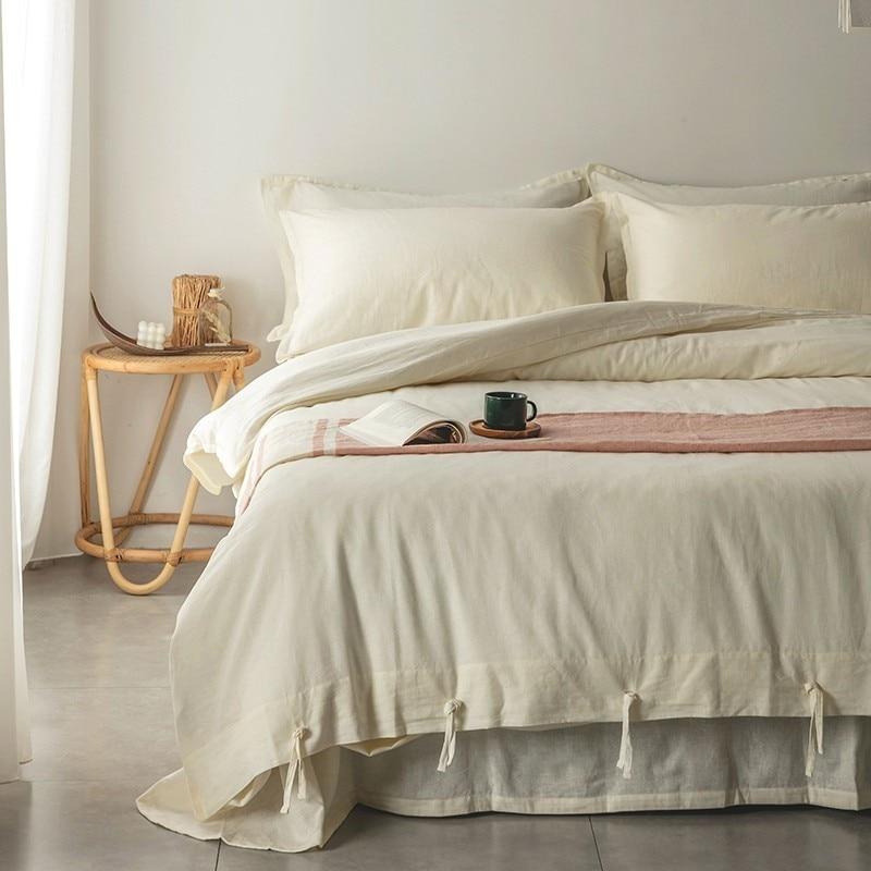 Emma Duvet Cover Set With Ropes 55% Cotton 45% Linen on a bed with cozy pillows and a side table.