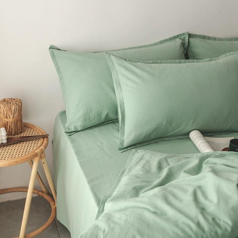 Emma Duvet Cover Set With Ropes 55% Cotton 45% Linen in green, displayed with pillows and a woven side table.