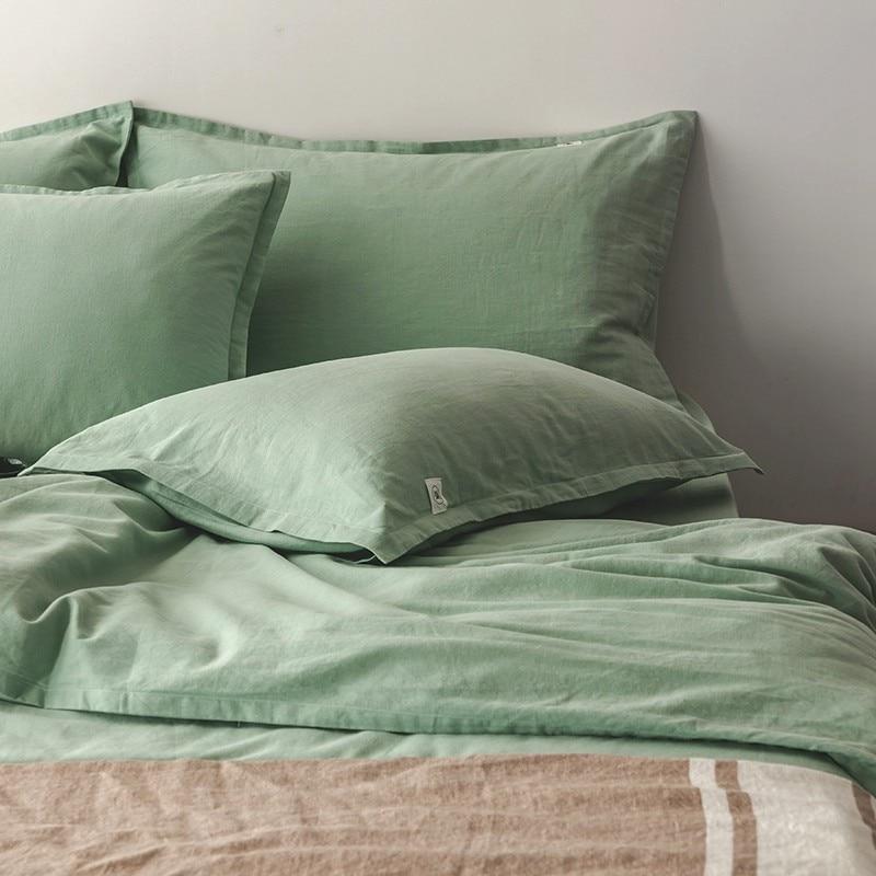 Emma Duvet Cover Set With Ropes 55% Cotton 45% Linen in soft green on bed with pillows and blanket