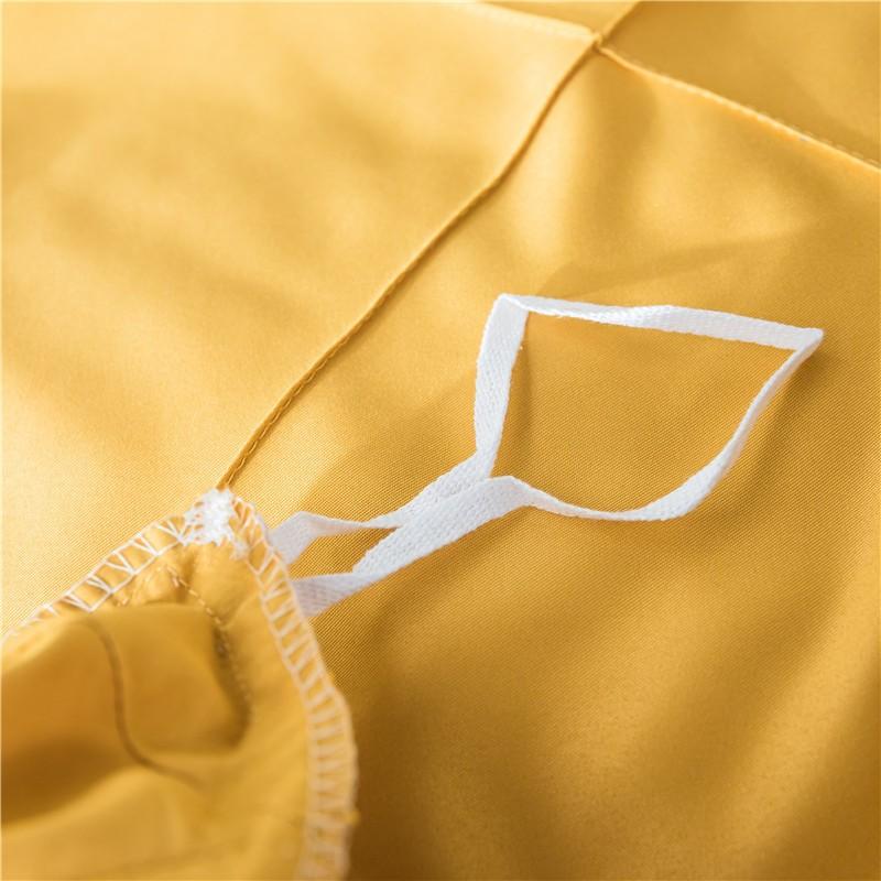 Close-up of Charlotte Ultra Soft Microfiber Duvet Cover Set fabric and corner tie in a warm yellow shade.