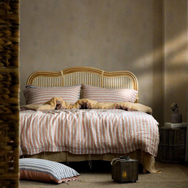 PeachPuff Vertical Stripes 100% Linen Duvet Cover Set on bed with woven headboard, showcasing cozy and breathable bedding.