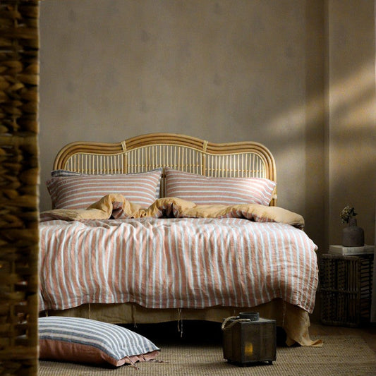 PeachPuff Vertical Stripes 100% Linen Duvet Cover Set on bed with woven headboard, showcasing cozy and breathable bedding.