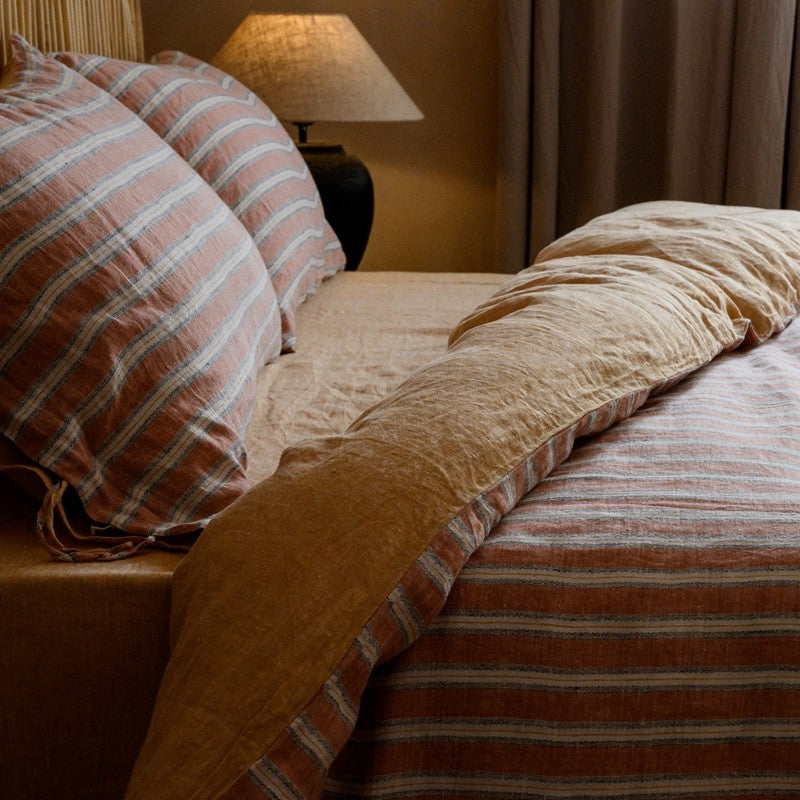 PeachPuff Vertical Stripes 100% Linen Duvet Cover Set on a cozy, soft bed with pre-washed fabric accents in a warm bedroom setting.