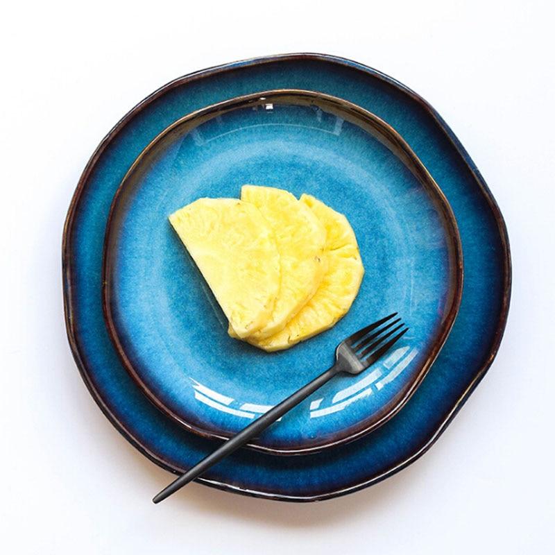 Slices of pineapple on a blue ceramic Taygete Plate with a solid pattern and round shape, accompanied by a black fork on the side.