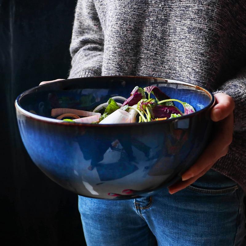 Person holding Tana Ceramic Bowl 2400ml filled with fresh salad, showcasing its eco-friendly porcelain design and solid pattern.