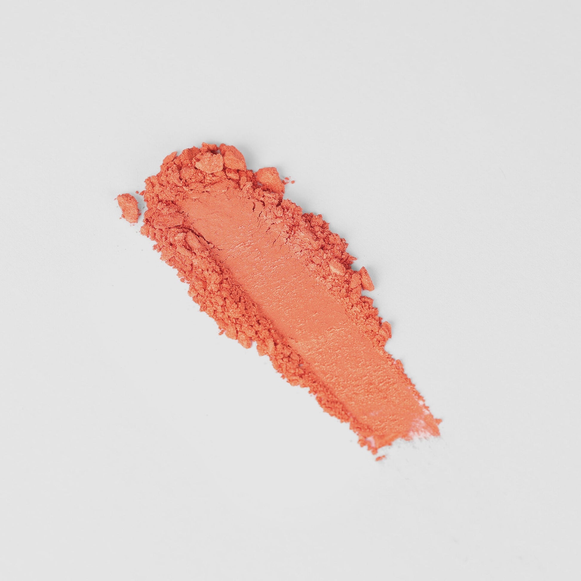 Vibrant orange vegan blush swatch showcasing smooth, blendable texture, perfect for customizable makeup palette organization.